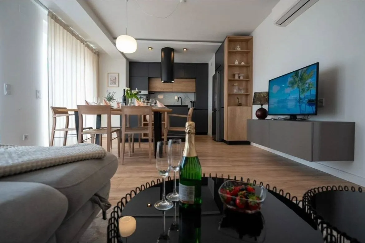 Dnevni boravak s visećim TV elementom i kuhinjom u pozadini